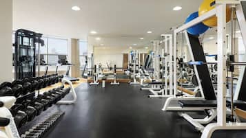 A gym with exercise equipment, treadmills, and weight racks.