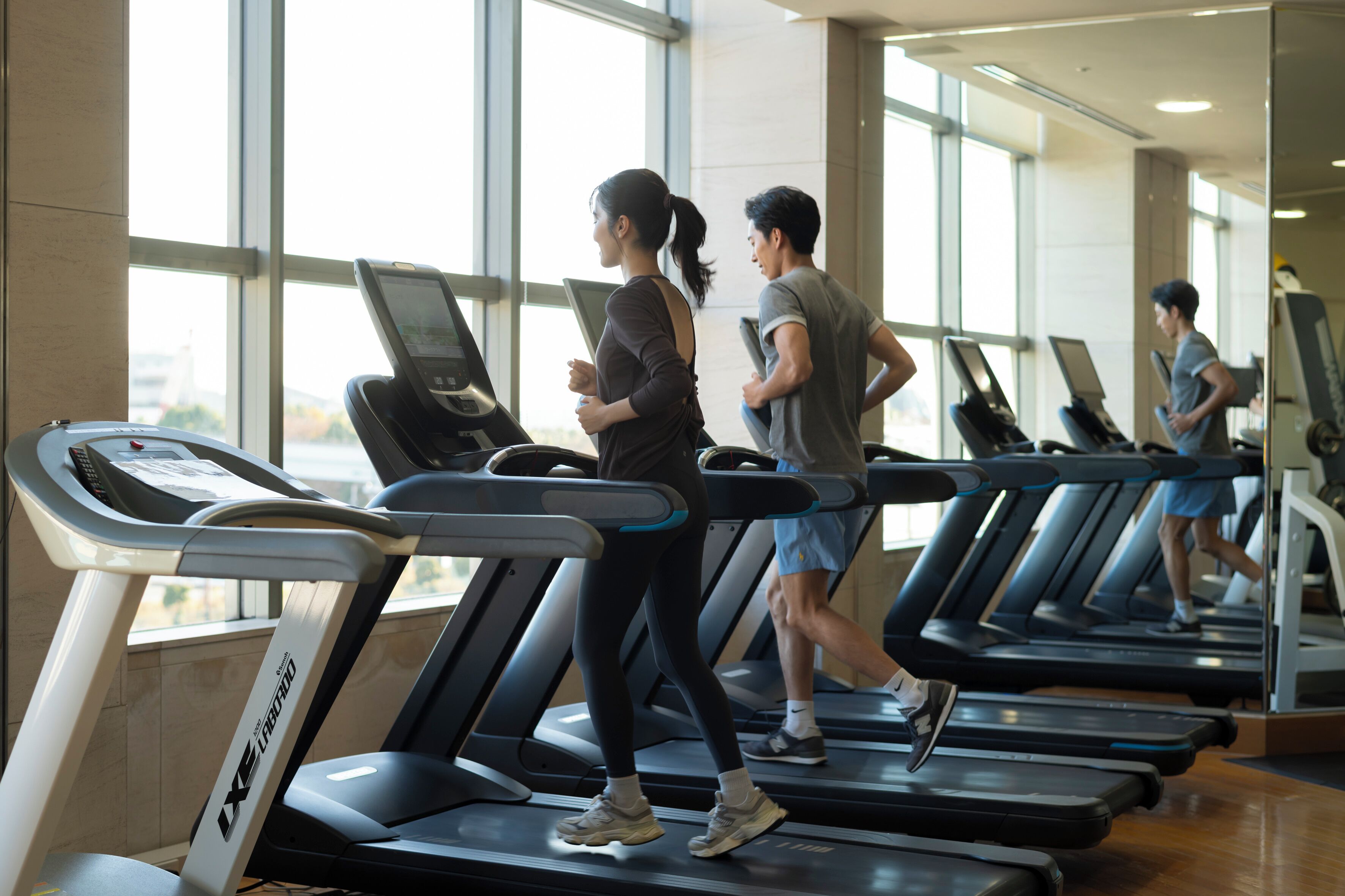 A gym with treadmills, large windows, and a modern interior.