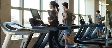 Un gimnasio con cintas de correr, amplios ventanales y un diseño moderno.