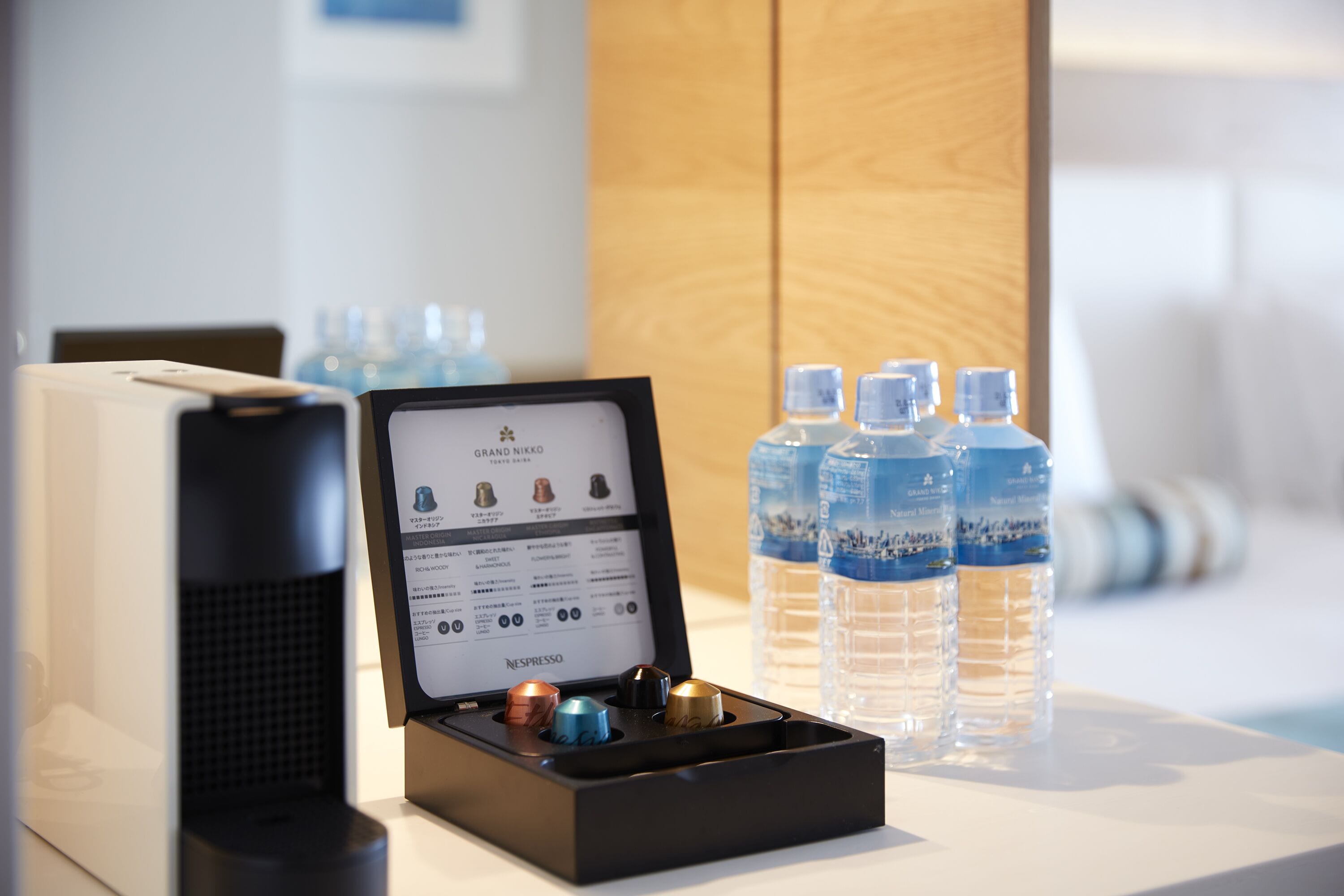 A coffee machine with a display screen, water bottles, and a coffee pod holder.