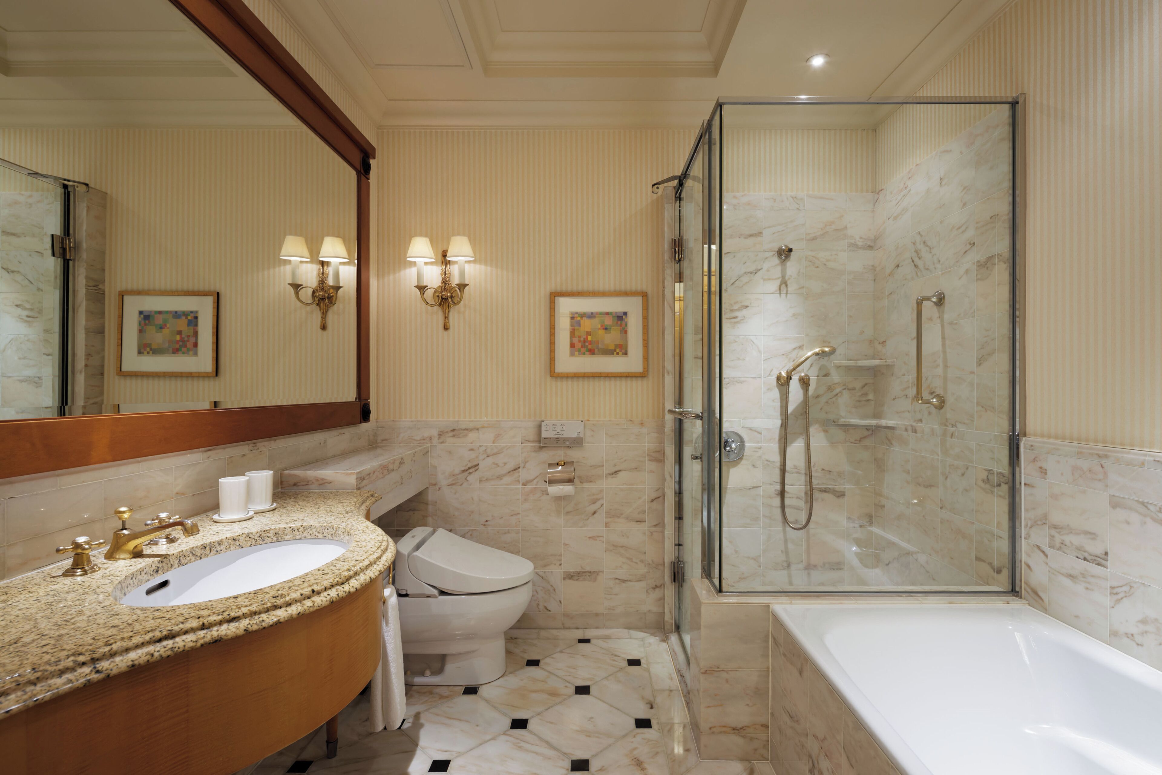 A bathroom with a marble sink, toilet, and a glass-enclosed shower.