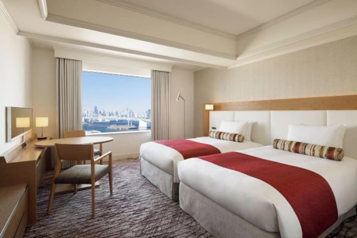 Une chambre d’hôtel avec deux lits, un bureau et une chaise.