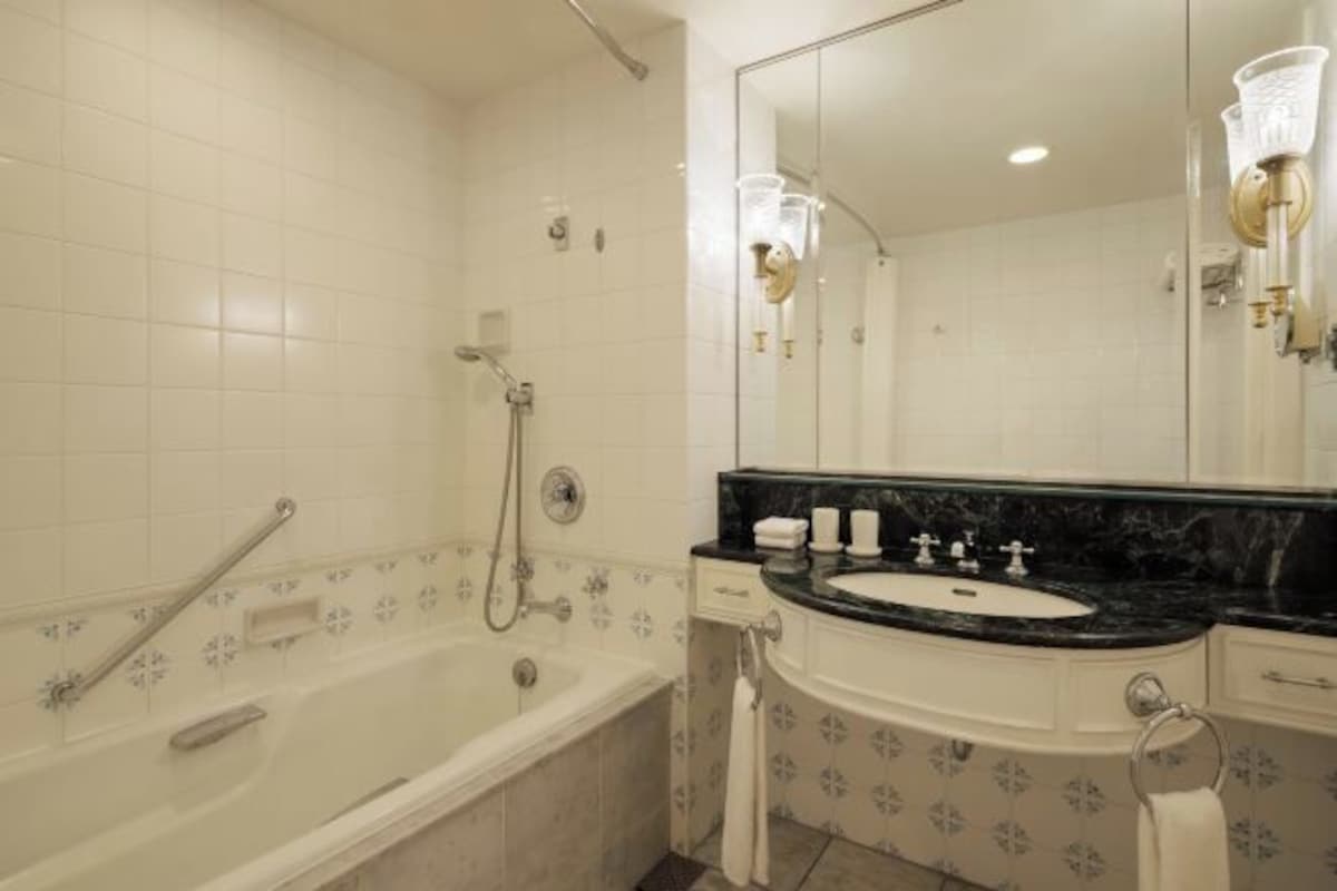 Une salle de bain avec une baignoire, un lavabo, un miroir et un porte-serviettes.
