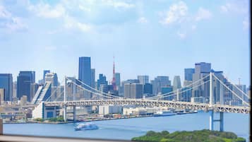 A city skyline with a prominent bridge spanning a river, modern buildings, and a clear sky.