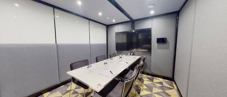 Una sala conferenze con un lungo tavolo, sedie e uno schermo per proiezioni.