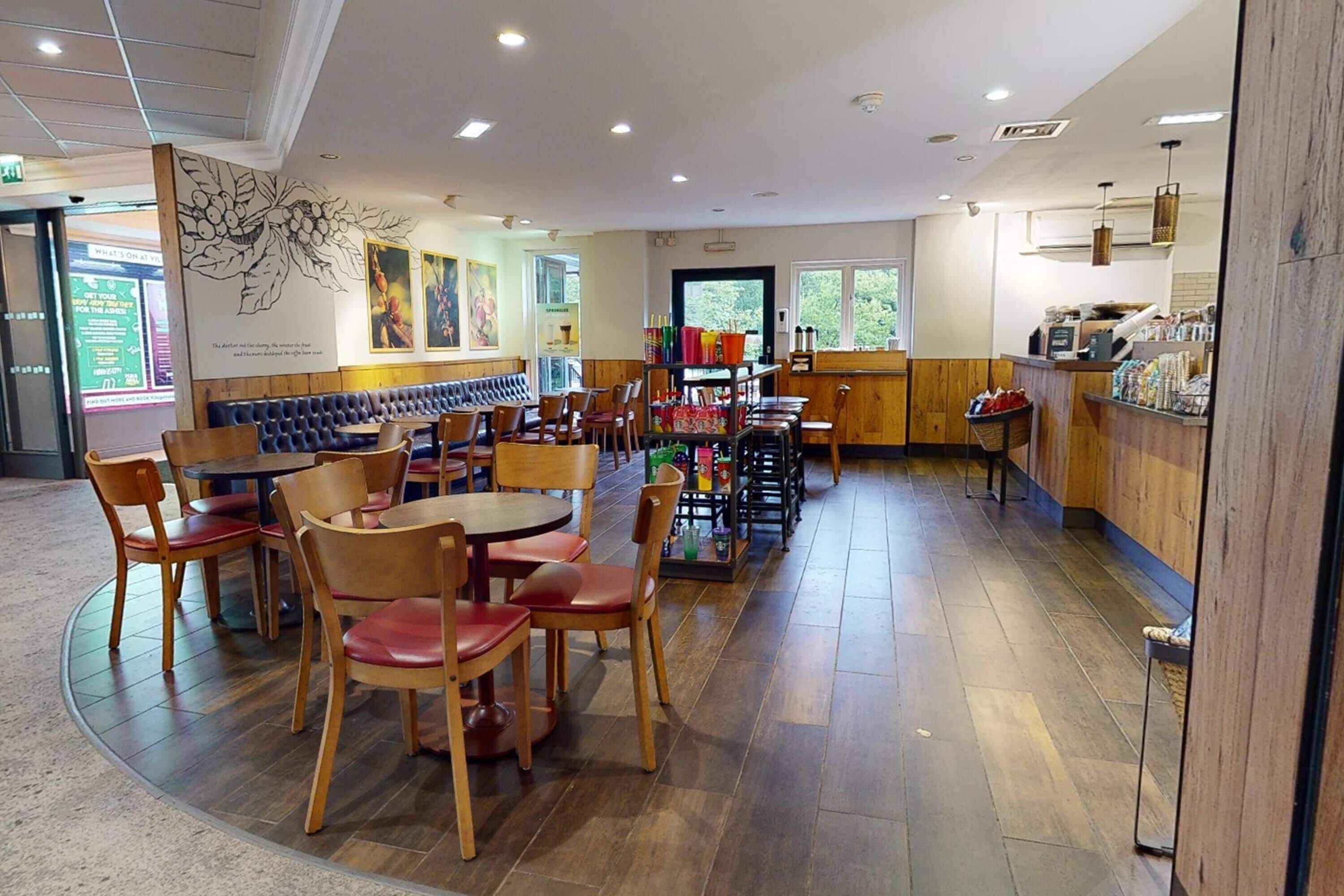 A restaurant with wooden tables and chairs, a counter with snacks, and a mural on the wall.