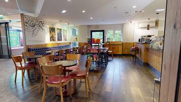Un restaurante con mesas y sillas de madera, una barra con aperitivos y un mural en la pared.