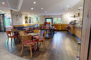 A restaurant with wooden tables and chairs, a counter with snacks, and a mural on the wall.