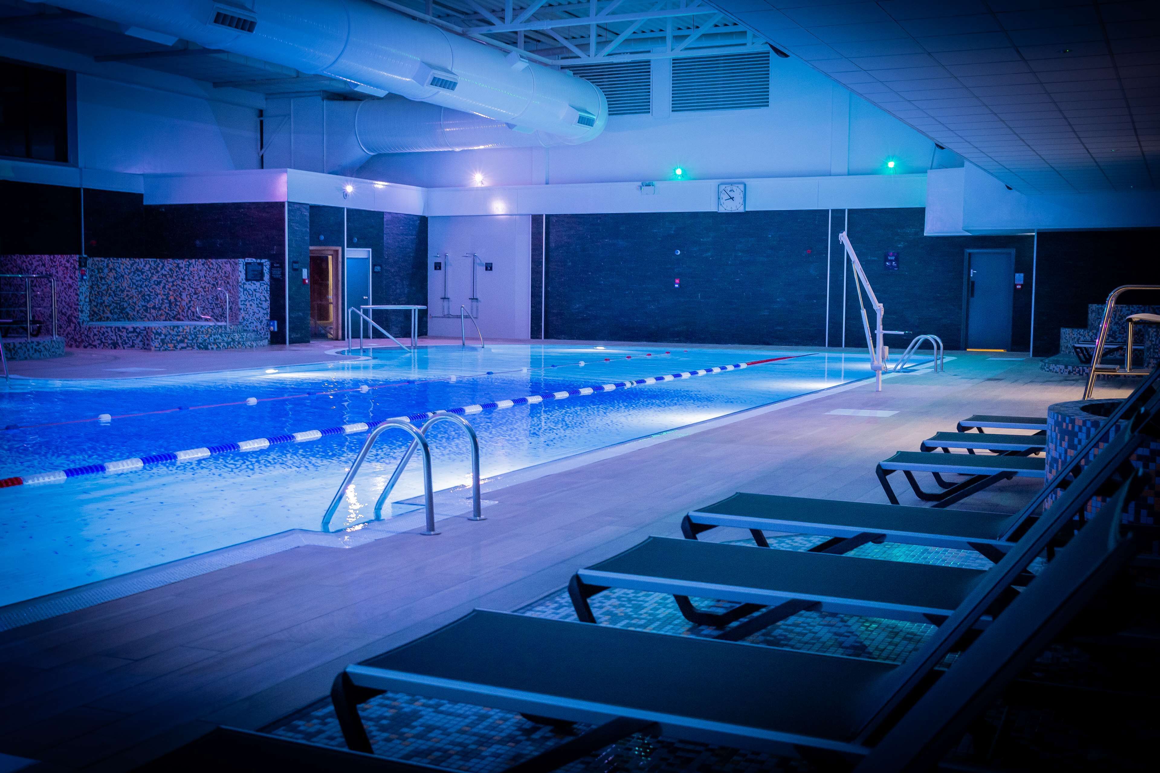 An indoor swimming pool with lanes, a changing room, and lounge chairs.
