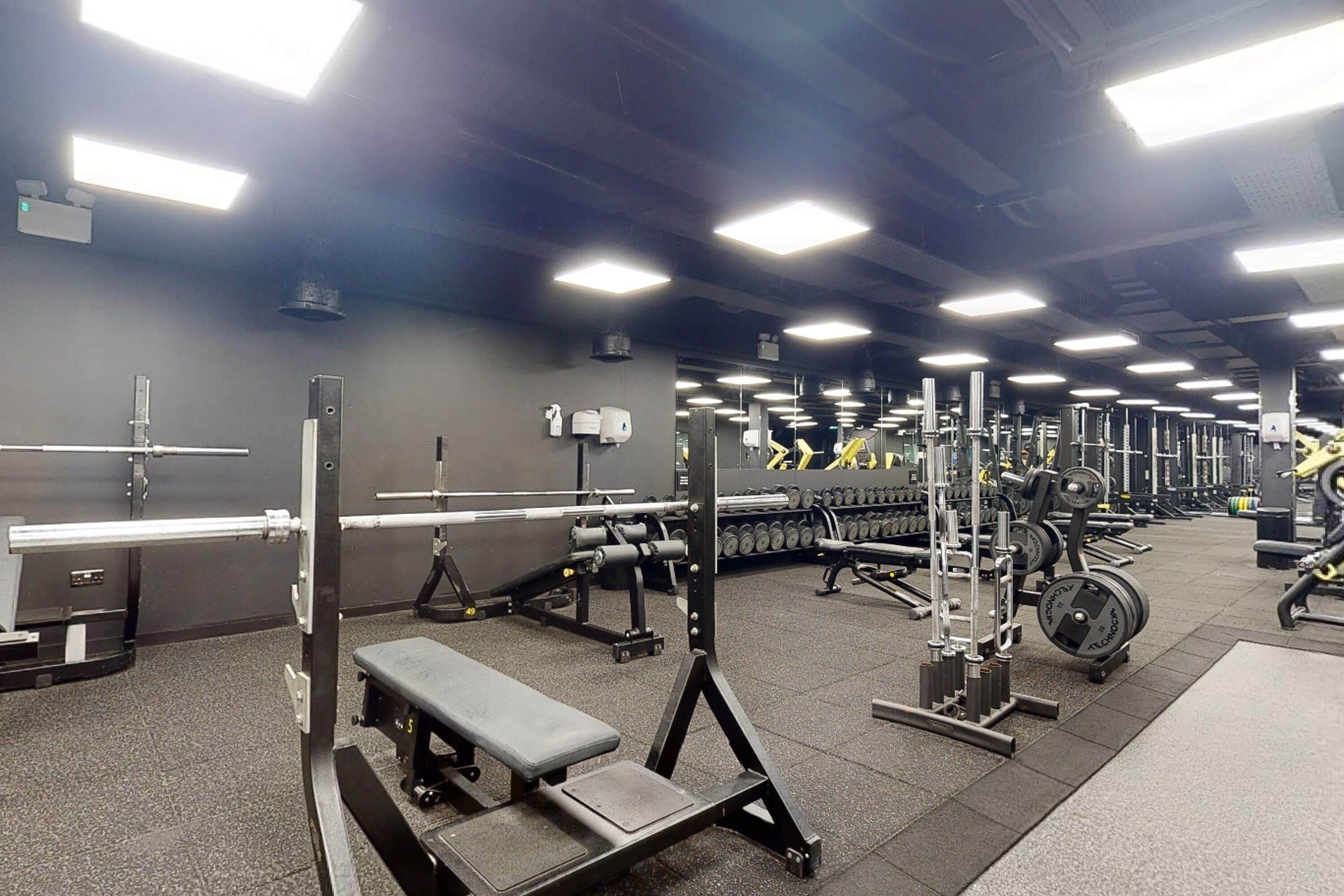 A gym with various exercise equipment, including benches, weight machines, and dumbbells.