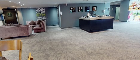 Et fitnesscenter med reception, sofa og stol.