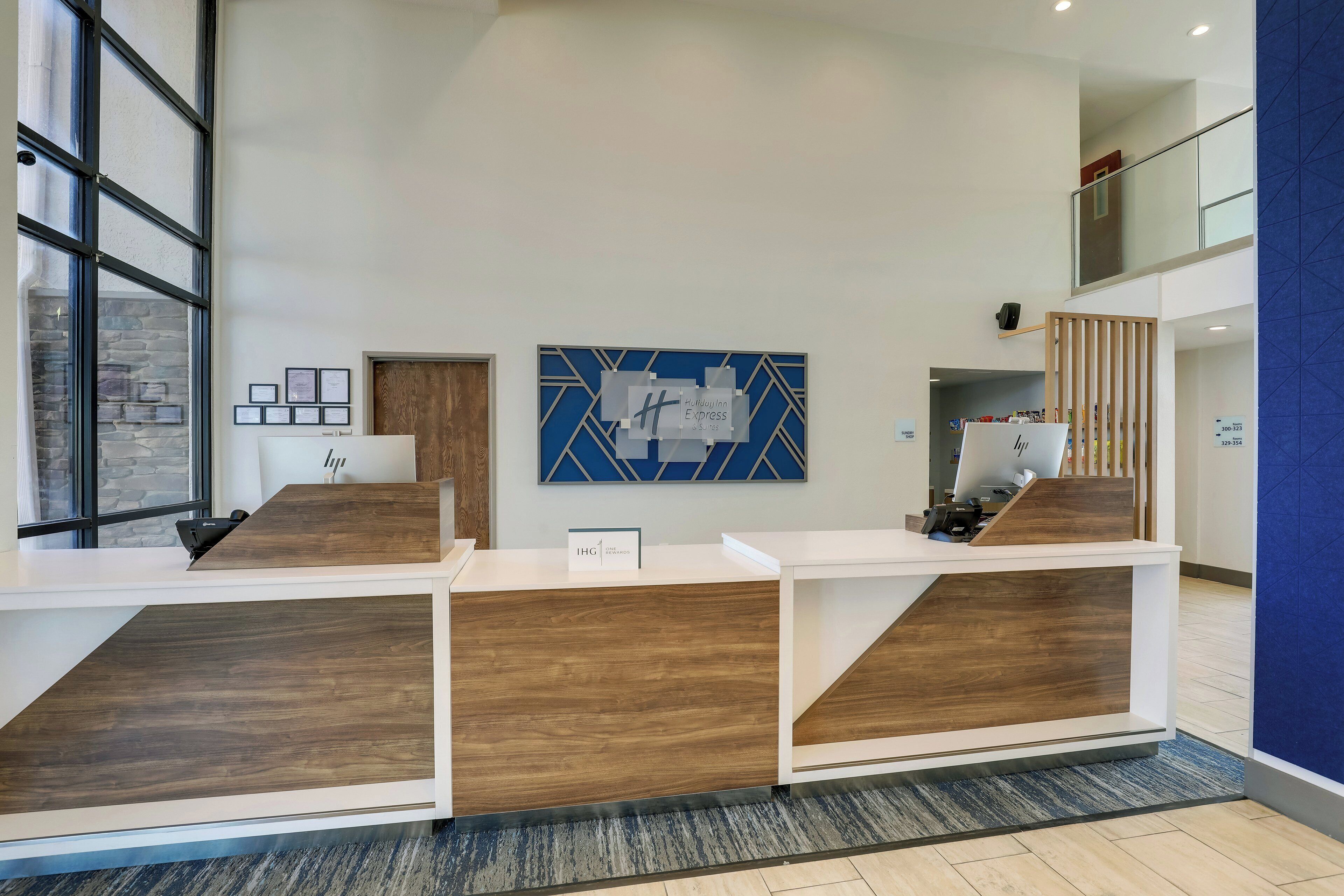 A reception desk with a modern design, featuring a wooden finish and a blue geometric wall art piece above it.