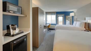 A hotel room with a bed, a desk, a microwave, a coffee maker, and a mini-fridge.