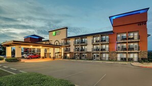 A hotel with multiple floors, a parking lot, and a red vehicle parked outside. - Holiday Inn Express Hotel & Suites Branson 76 Central by IHG (Branson)