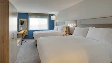 Una habitación de hotel con dos camas, un escritorio, una silla y un espejo.