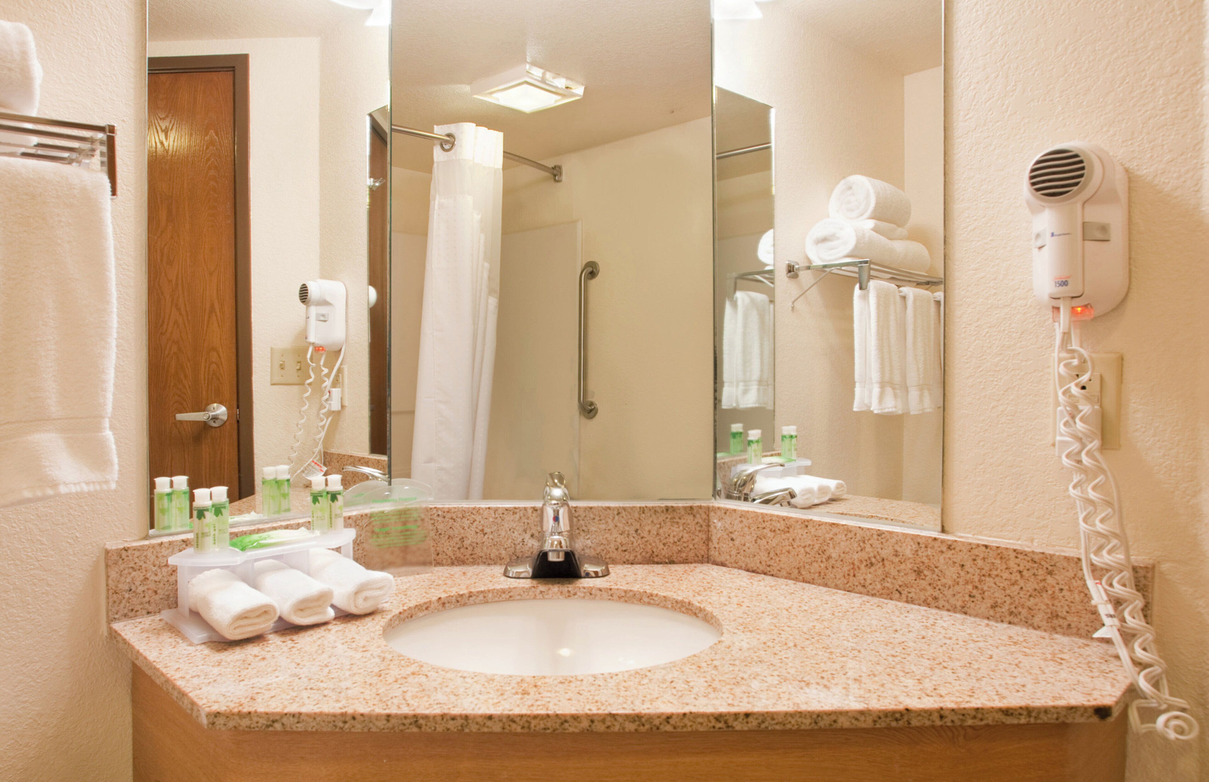 A hotel bathroom with a sink, mirror, towel rack, and a hairdryer.