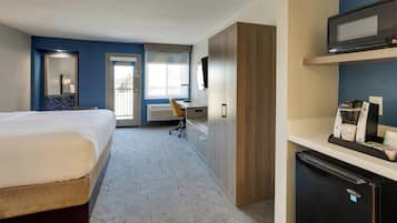 Een hotelkamer met een bed, bureau, stoel, kledingkast en een minibar.