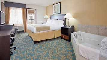 A hotel room with a bed, bedside tables, a desk, a chair, a bathroom with a bathtub, and a window with curtains.