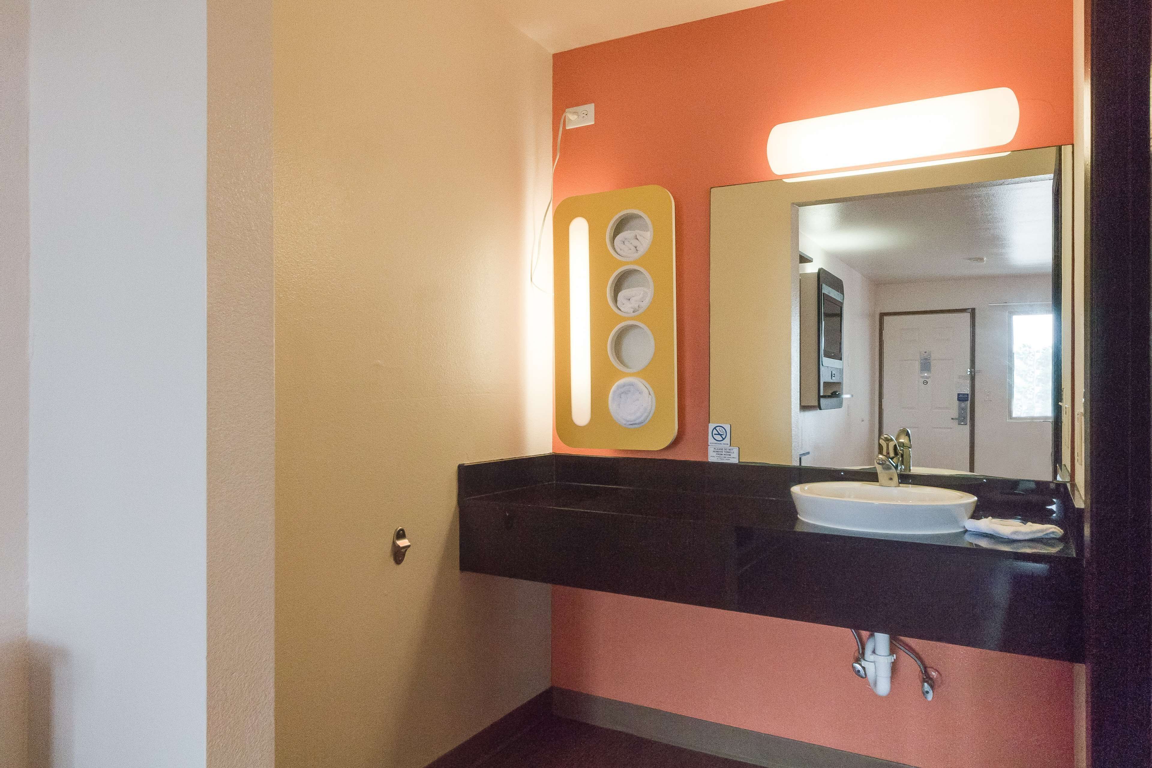 A bathroom with a black sink, a mirror, and a wall-mounted light fixture.