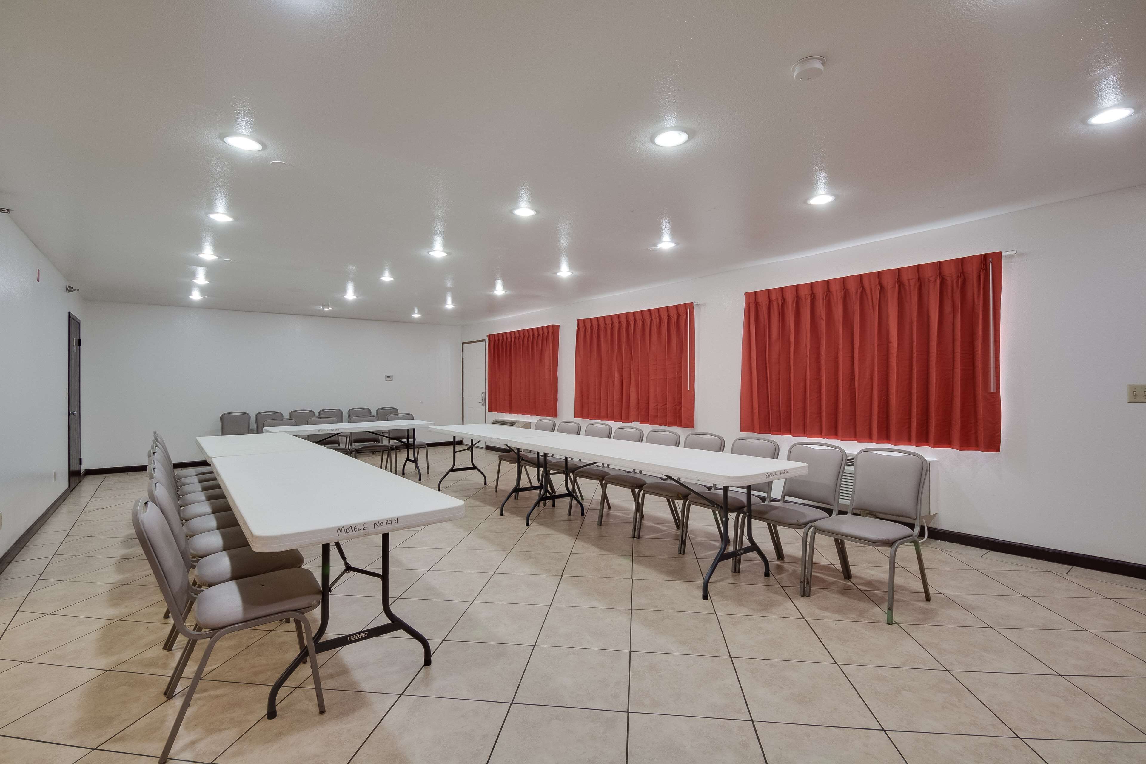 A conference room with a long table, chairs, and red curtains.