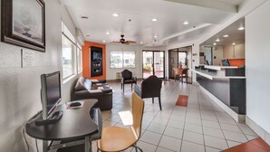 A modern hotel lobby with a reception desk, seating area, and a large window.