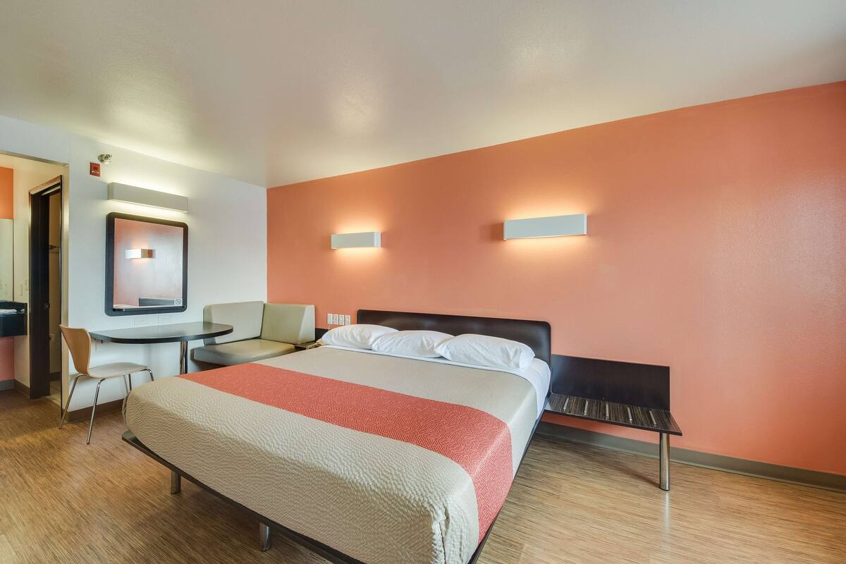 Une chambre d’hôtel avec un lit, un bureau, une chaise et un banc.