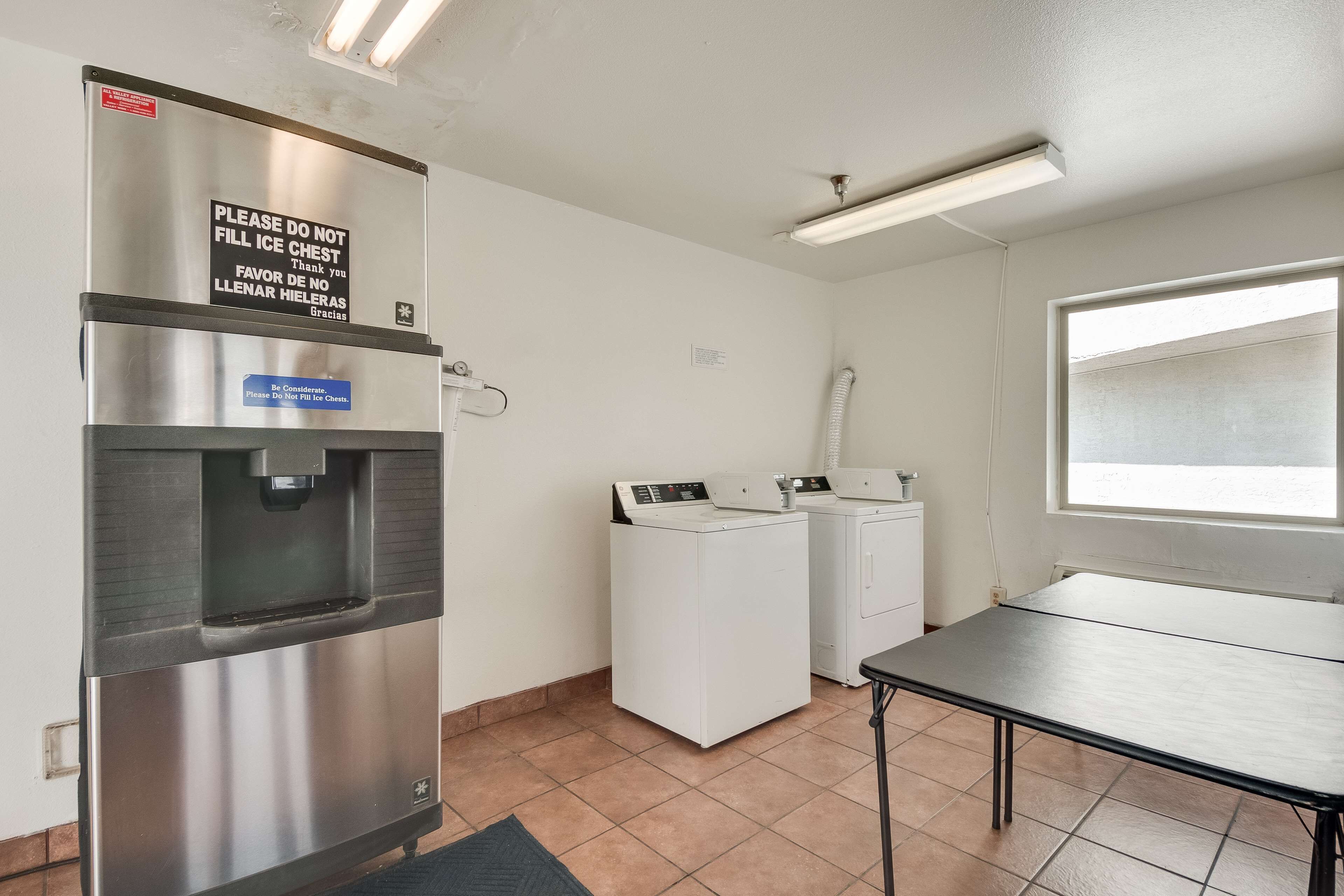 A laundry area with a stainless steel refrigerator, a water dispenser, and two washing machines.