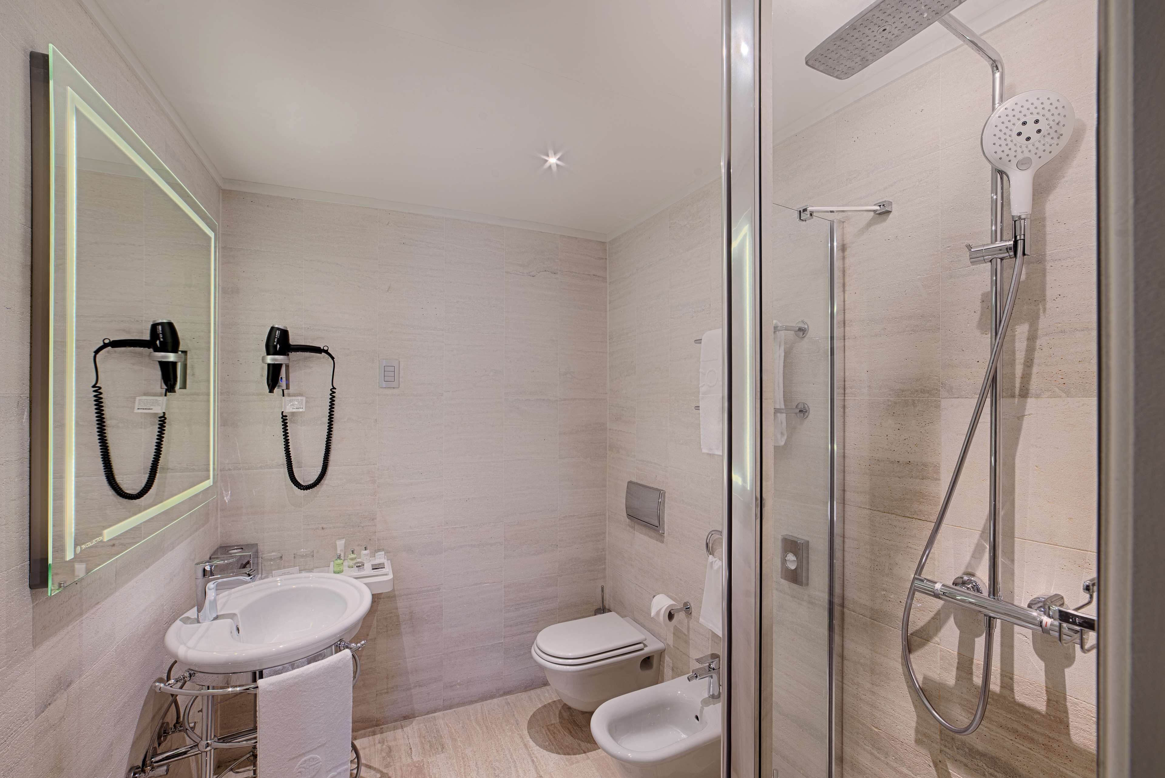 A modern bathroom with a glass-enclosed shower, a sink, and a toilet.