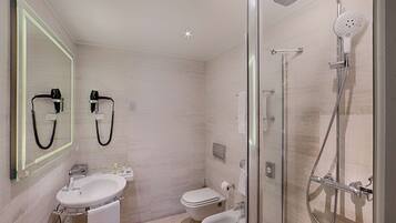 A modern bathroom with a glass-enclosed shower, a sink, and a toilet.