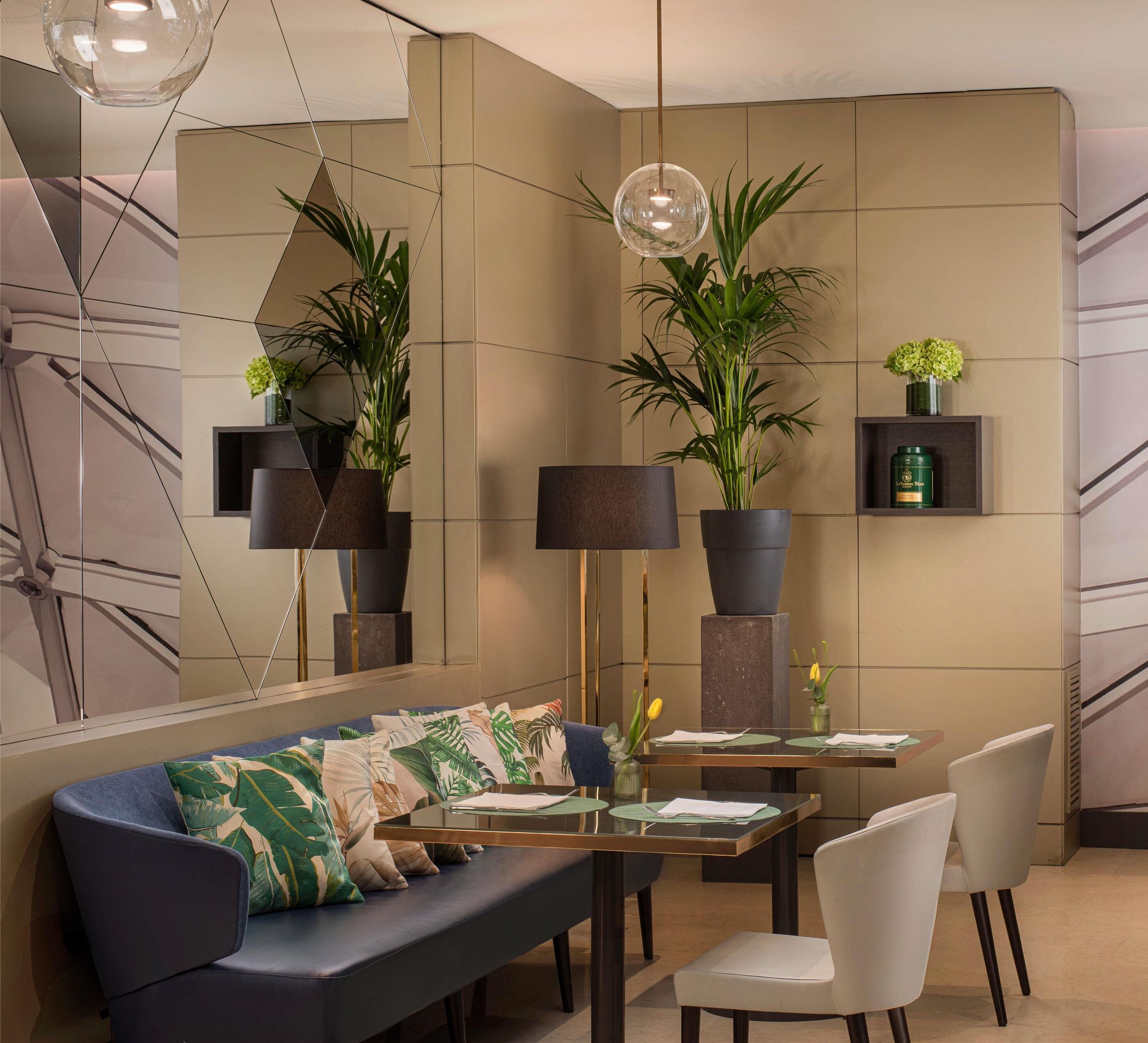 Un comedor moderno con sofá, mesa, sillas y plantas en macetas.