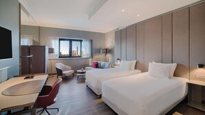 A hotel room with two beds, a desk, a chair, a small table, and a window with curtains. - NH Collection Milano Porta Nuova (Milan)