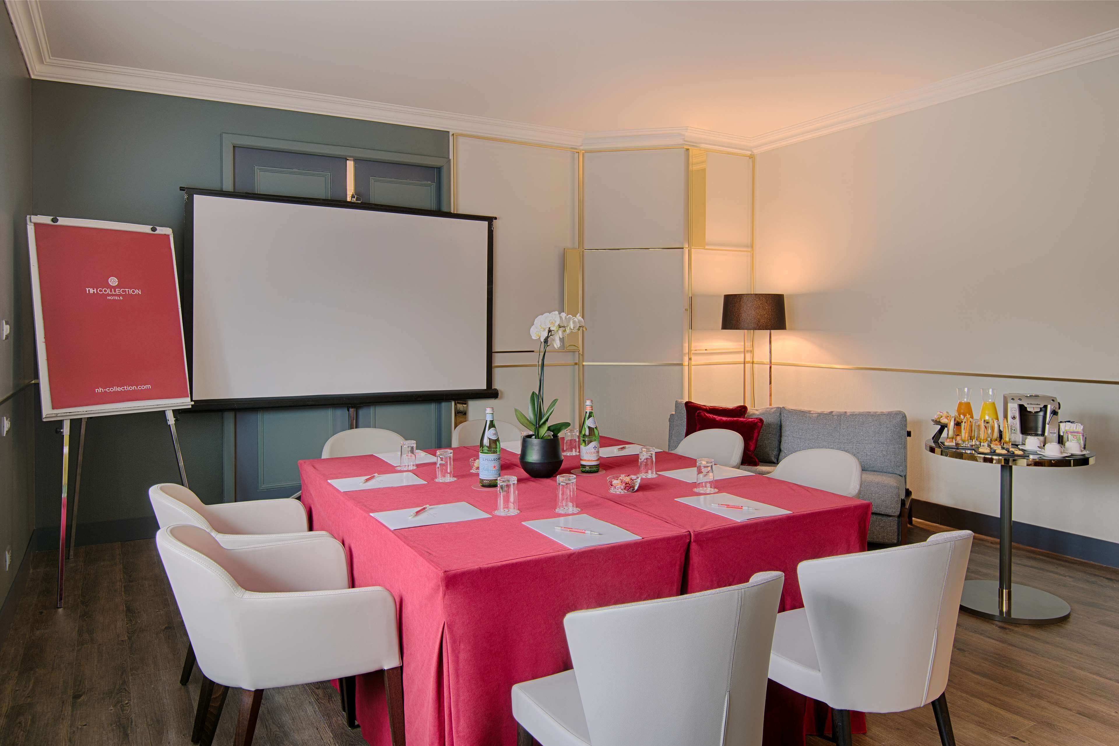 A conference room with a whiteboard, a projector, and a table set for a meeting.