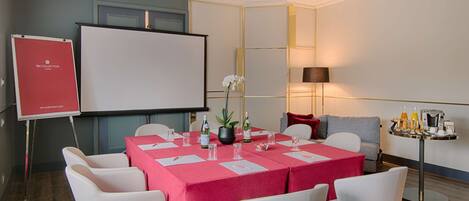 A conference room with a whiteboard, a projector, and a table set for a meeting.