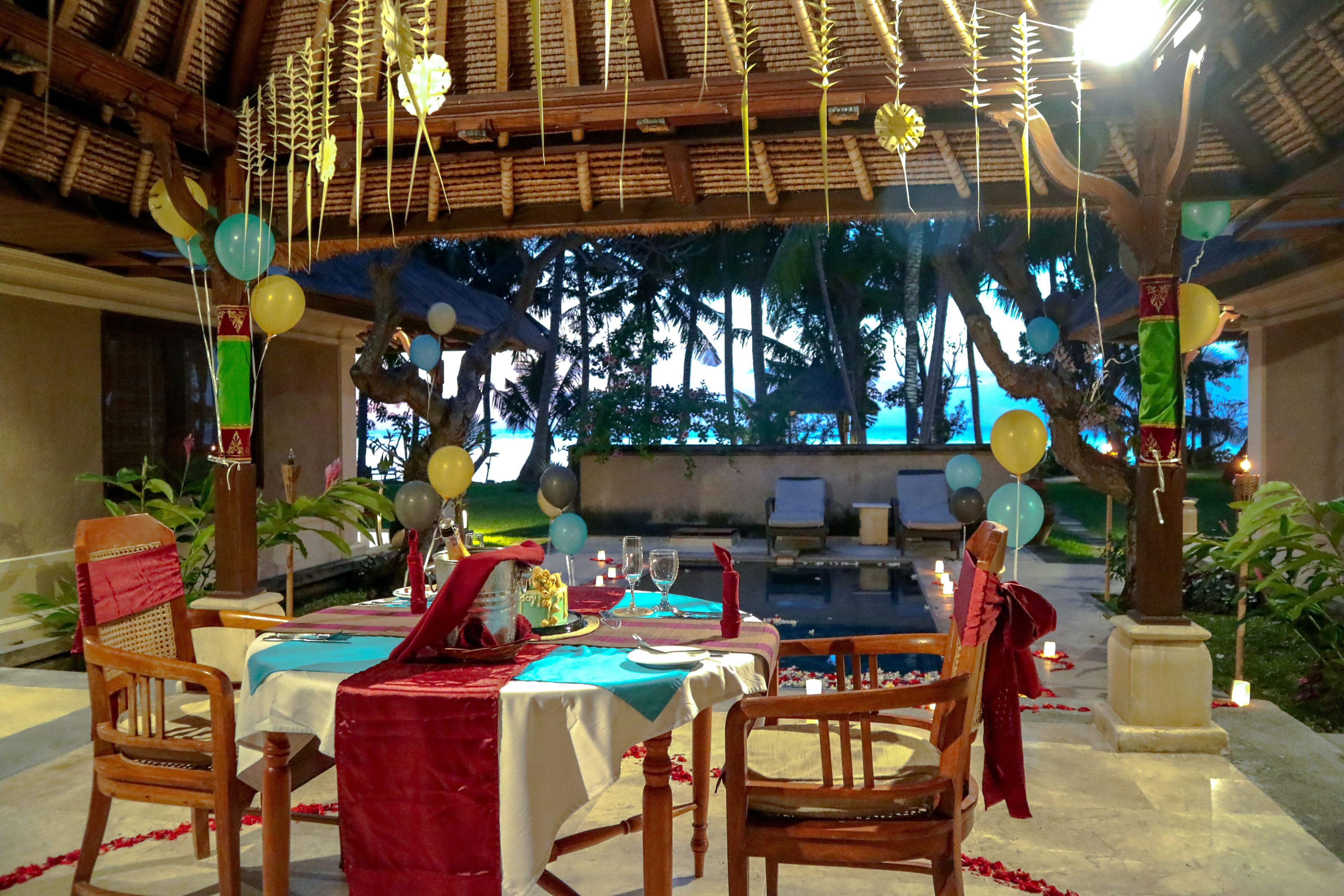 Un área de comedor con vista a la piscina, decorada con globos y velas.