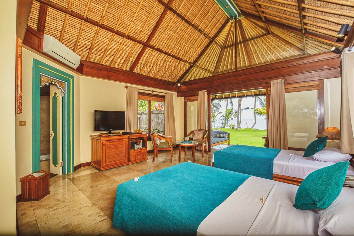 A hotel room with two beds, a TV, a desk, and a view of the outdoors.