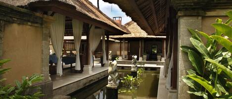 A traditional thatched-roof building with a water feature in the foreground.