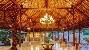 A spacious lobby with a high ceiling, a central chandelier, and a reception desk. - Puri Bagus Lovina (Buleleng)