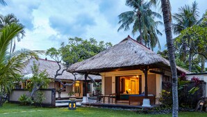 A resort with thatched-roof cottages, a well-maintained lawn, and tropical vegetation. - Puri Bagus Lovina (Buleleng)