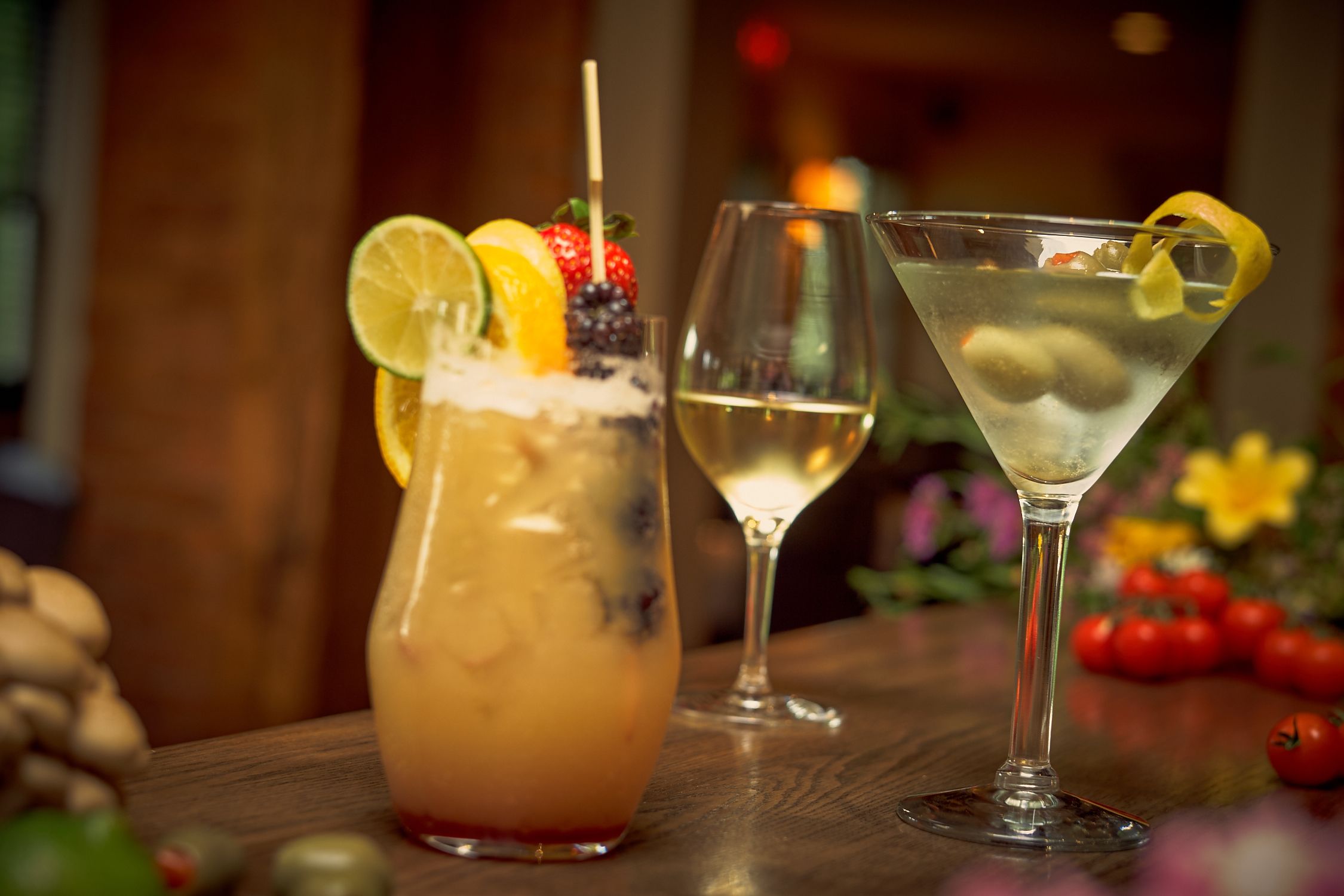 Two cocktails on a wooden table with a blurred background.