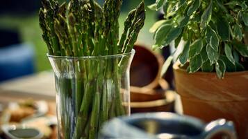 A glass containing asparagus with a blurred background of a table setting.