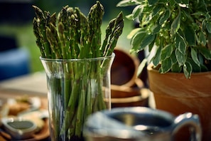 A glass containing asparagus with a blurred background of a table setting. - Auberge West Brome (Lac-Brome)