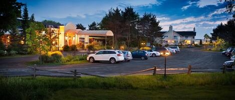 A parking lot with several cars and a building with a covered area.