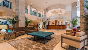 A spacious lobby with a reception desk, seating areas, and a staircase. - Best Western Plus Atlantic Beach Resort (Miami Beach)