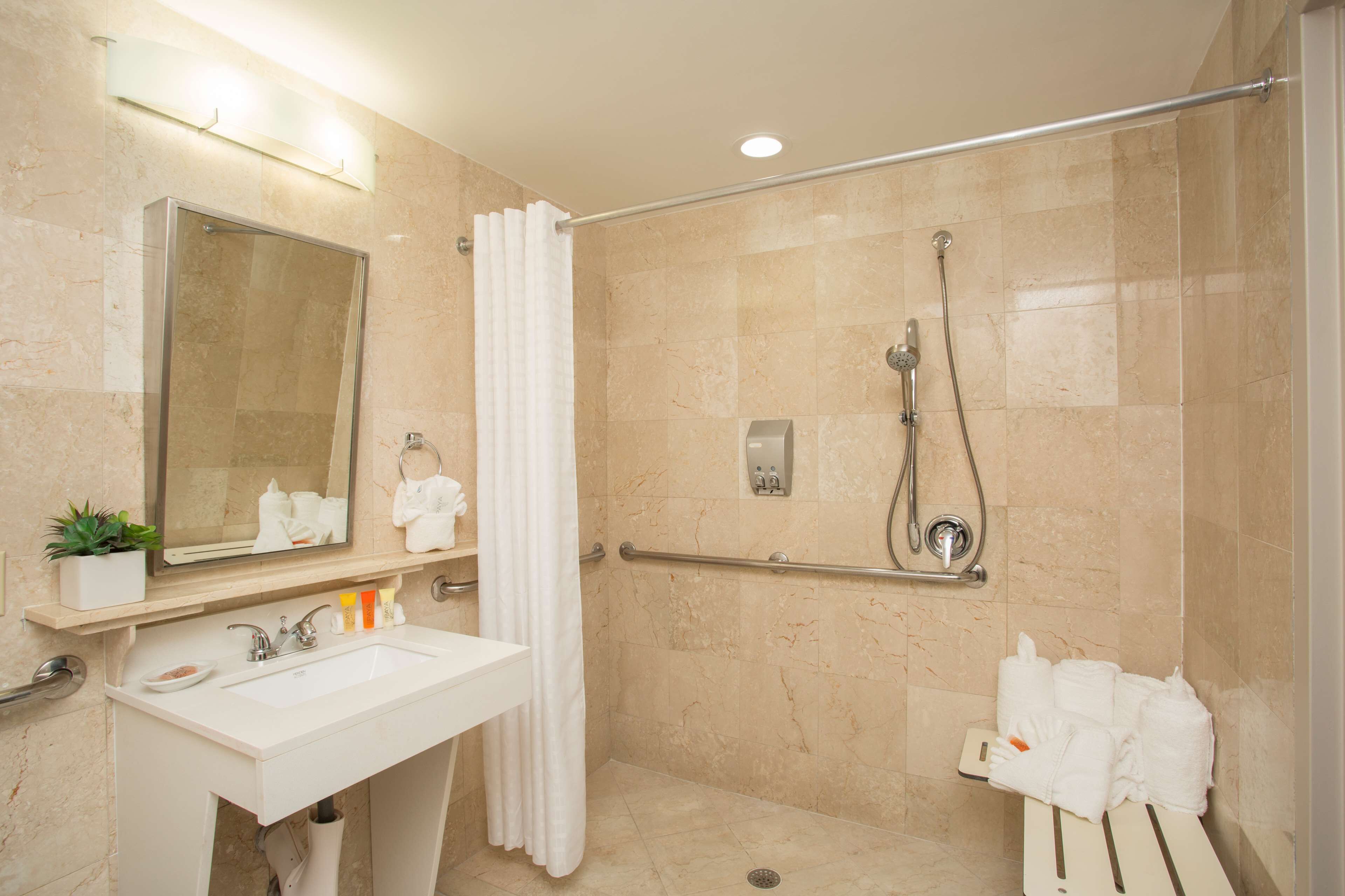 A modern bathroom with a glass-enclosed shower, a sink, and a mirror.