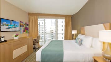 A hotel room with a bed, a desk, a chair, a TV, and a window with curtains.