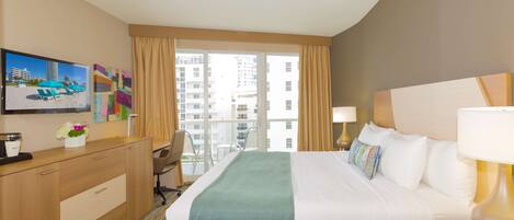 A hotel room with a bed, a desk, a chair, a TV, and a window with curtains.