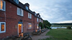 A brick building with a row of picnic tables and lanterns, suggesting an outdoor dining area. - Master Builders House Hotel (Brockenhurst)