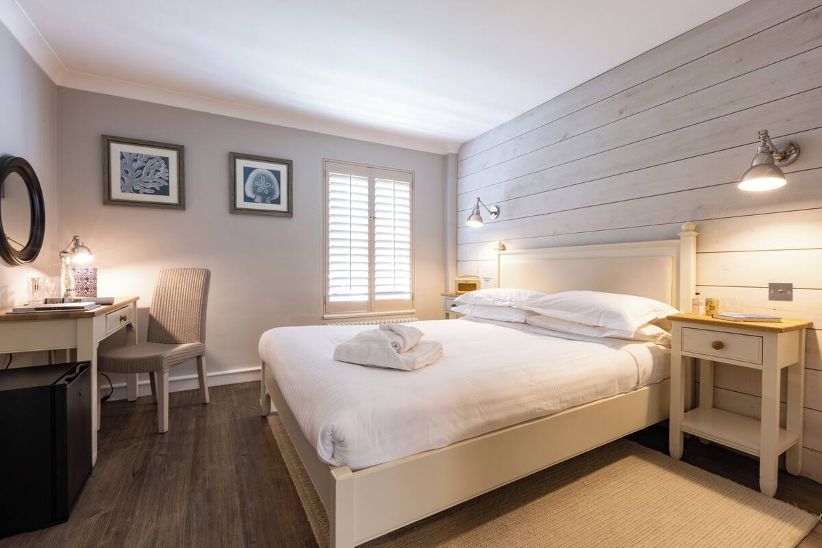 A bedroom with a bed, bedside tables, a desk, and a chair.