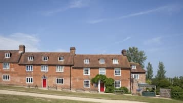 A large, multi-story brick building with a red door and multiple windows.