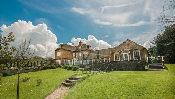 A large brick house with a well-maintained lawn, a pathway leading to the entrance, and a staircase. - Master Builders House Hotel (Brockenhurst)